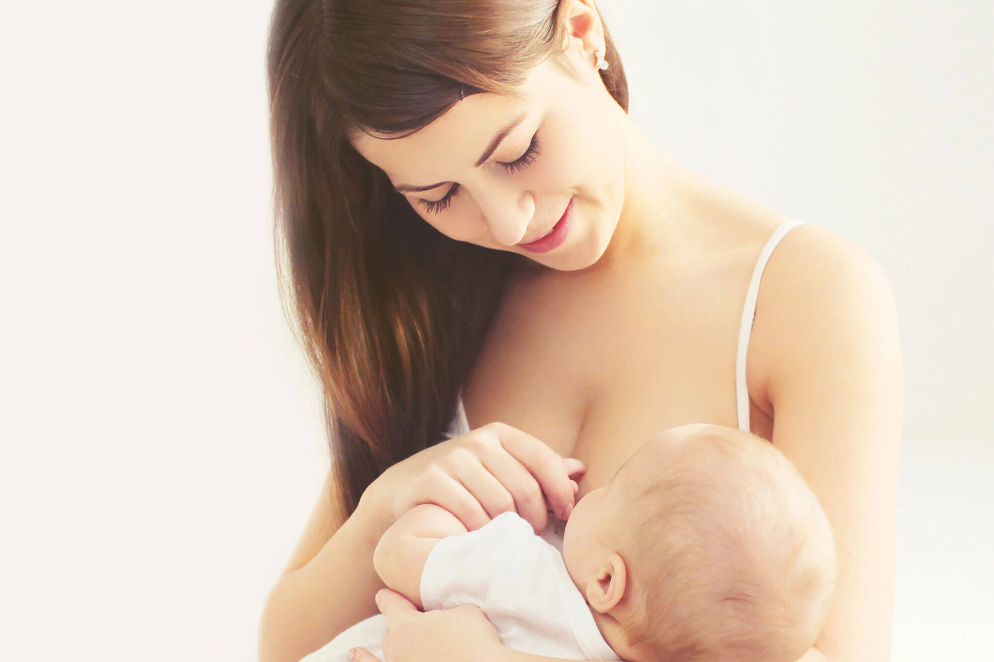 Frau stillt Baby liebevoll.